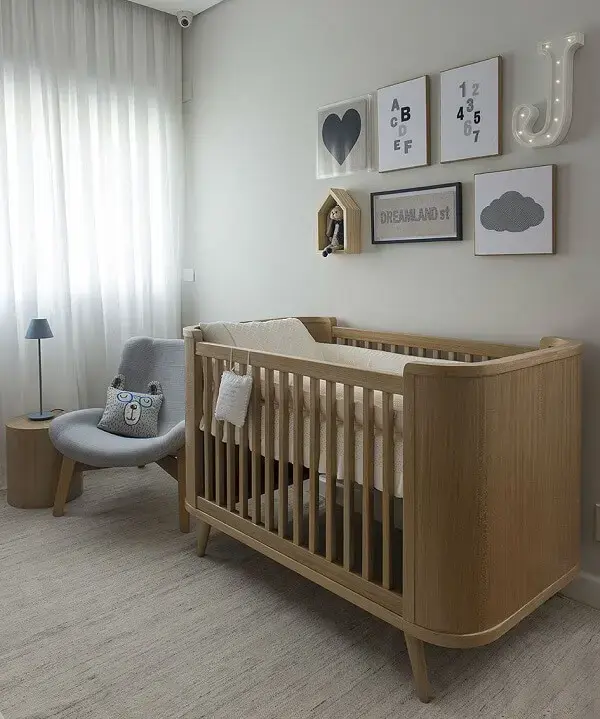 Quarto de bebê decorado com poltrona cinza de amamentação e berço de madeira Quarto de bebê decorado com poltrona cinza de amamentação e berço de madeira