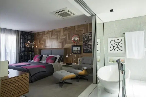 Quarto de casal com parede revestida de madeira e poltrona cinza confortável Quarto de casal com parede revestida de madeira e poltrona cinza confortável