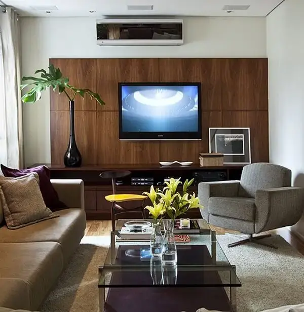 Sala de estar decorada com poltrona cinza giratória e mesa de centro de vidro Sala de estar decorada com poltrona cinza giratória e mesa de centro de vidro
