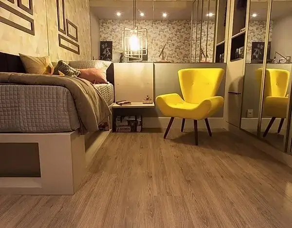 Quarto com parede espelhada e piso laminado