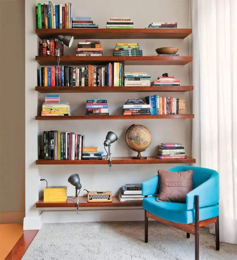 Decoração com prateleiras de madeira para livros e poltrona confortável para leitura Decoração com prateleiras de madeira para livros e poltrona confortável para leitura Foto Jeito de Casa