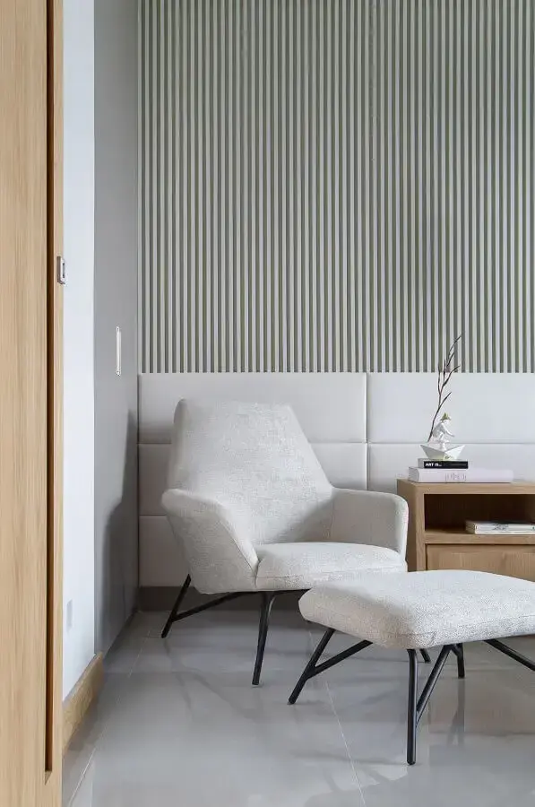 Poltrona confortável para quarto decorado com papel de parede listrado e cabeceira branca estofada Poltrona confortável para quarto decorado com papel de parede listrado e cabeceira branca estofada Foto Casa de Valentina