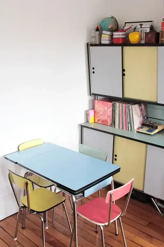 Sala pequena com pé de mesa retrô de ferro e cadeiras coloridas vintage