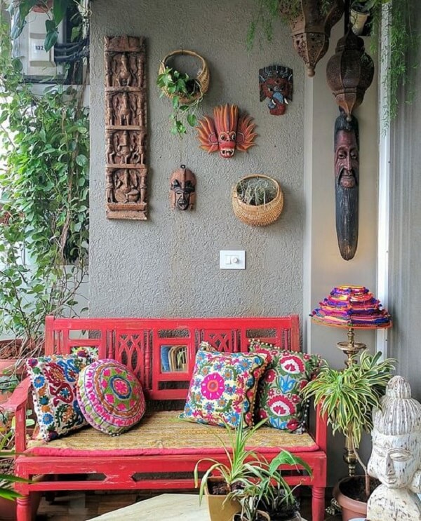Banco de jardim coral com almofadas coloridas e luminária de jardim vintage ao lado