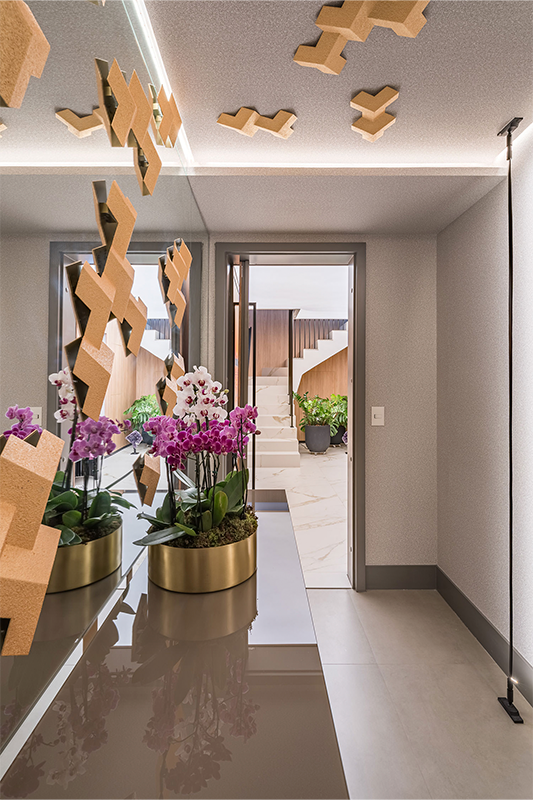 Projeto: Spaço Interior - Ana Rozenblit | No hall, espelhos no teto e na parede recebem a obra Padrone, de Rapha Preto, uma peça versátil que se adapta a diferentes formatos e composições.