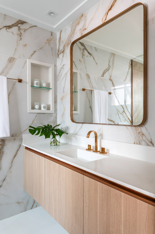 1. Torneira rose gold em contraste com revestimento marmorizado e madeira clara – Foto: Renato Navarro | Projeto: Erica Salguero Arquitetura