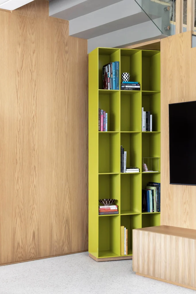 4. Estante colorida aproveita o canto e cria contraste com o painel de madeira – Foto: Bia Nauiack/Divulgação | Projeto: Ana Weege