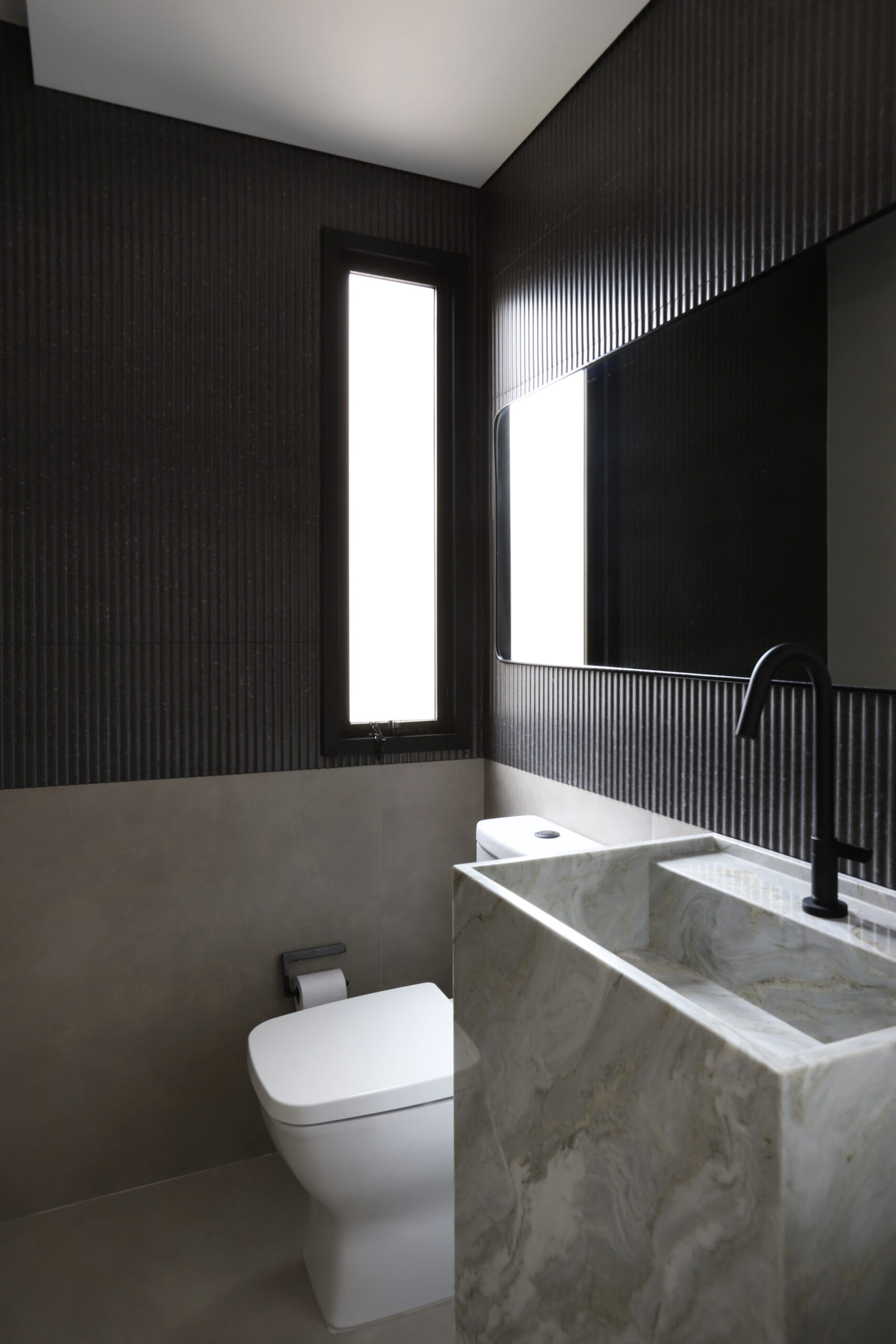 Mariana OrsiEstética marcada por contrastes entre superfícies escuras, louça branca e metais em matte black, cria composição de forte personalidade