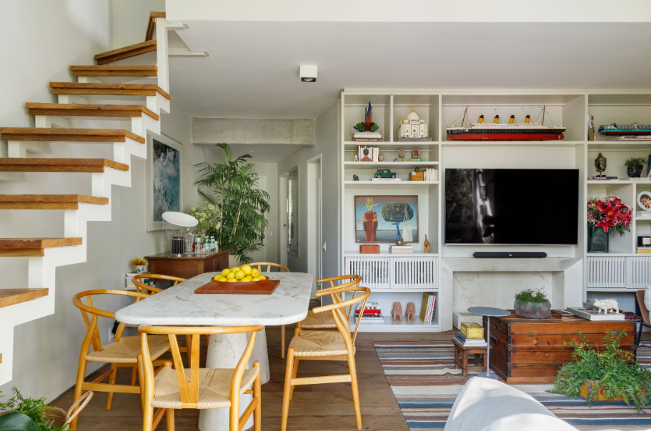 A lareira embutida na marcenaria e o tampo da mesa de jantar foram executados em mármore branco Paraná – Foto: Grutz Fotografia/CASACOR