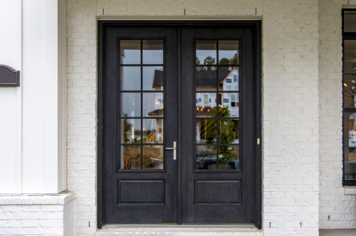 Porta francesa de madeira escura com divisões de vidro usada como entrada principal da casa – Foto: Freepik