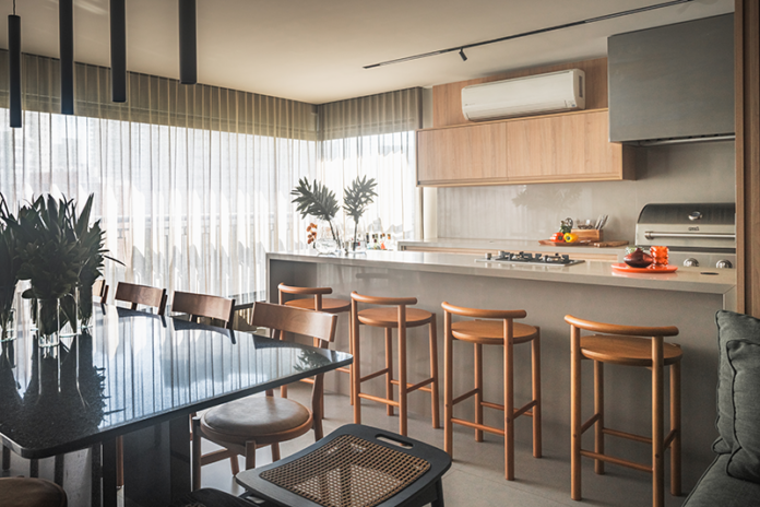 Neste projeto, a península com banquetas é um convite à convivência, enquanto o home bar, a adega e a cervejeira reforçam o espírito festeiro da família. Com o suporte da churrasqueira, do cooktop e da coifa, tudo funciona de forma prática e integrada à sala de jantar, sem abrir mão do conforto