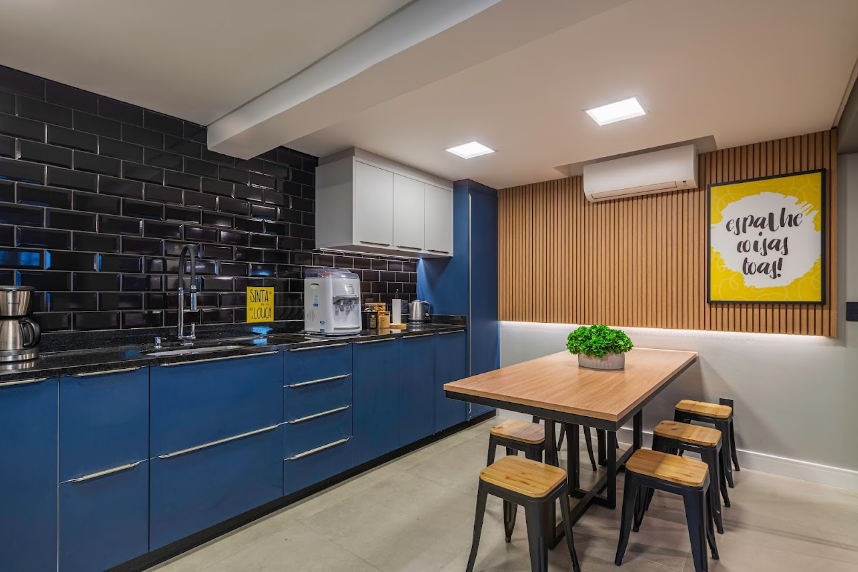 5. Cozinha contemporânea com influência industrial, marcada por marcenaria azul, revestimento preto tipo metrô, bancada escura e painel ripado em madeira – Foto: Alexzs | Projeto: Rötter Arquitetura