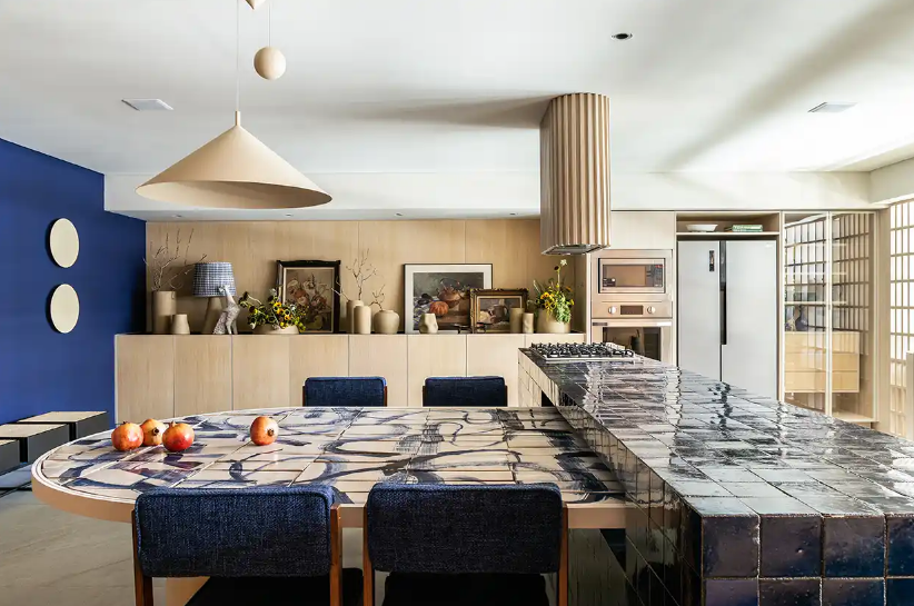 6. Parede em azul royal, ilha revestida em azulejo escuro e marcenaria em madeira clara – Foto: Israel Gollino/CASACOR | Projeto: Mandril Arquitetura