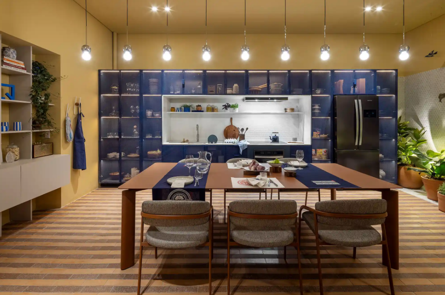 7. Azul royal nos detalhes: passadeira na mesa e aventais contrastando com o amarelo das paredes – Foto: Jomar Bragança/CASACOR | Projeto: Balsa Arquitetura